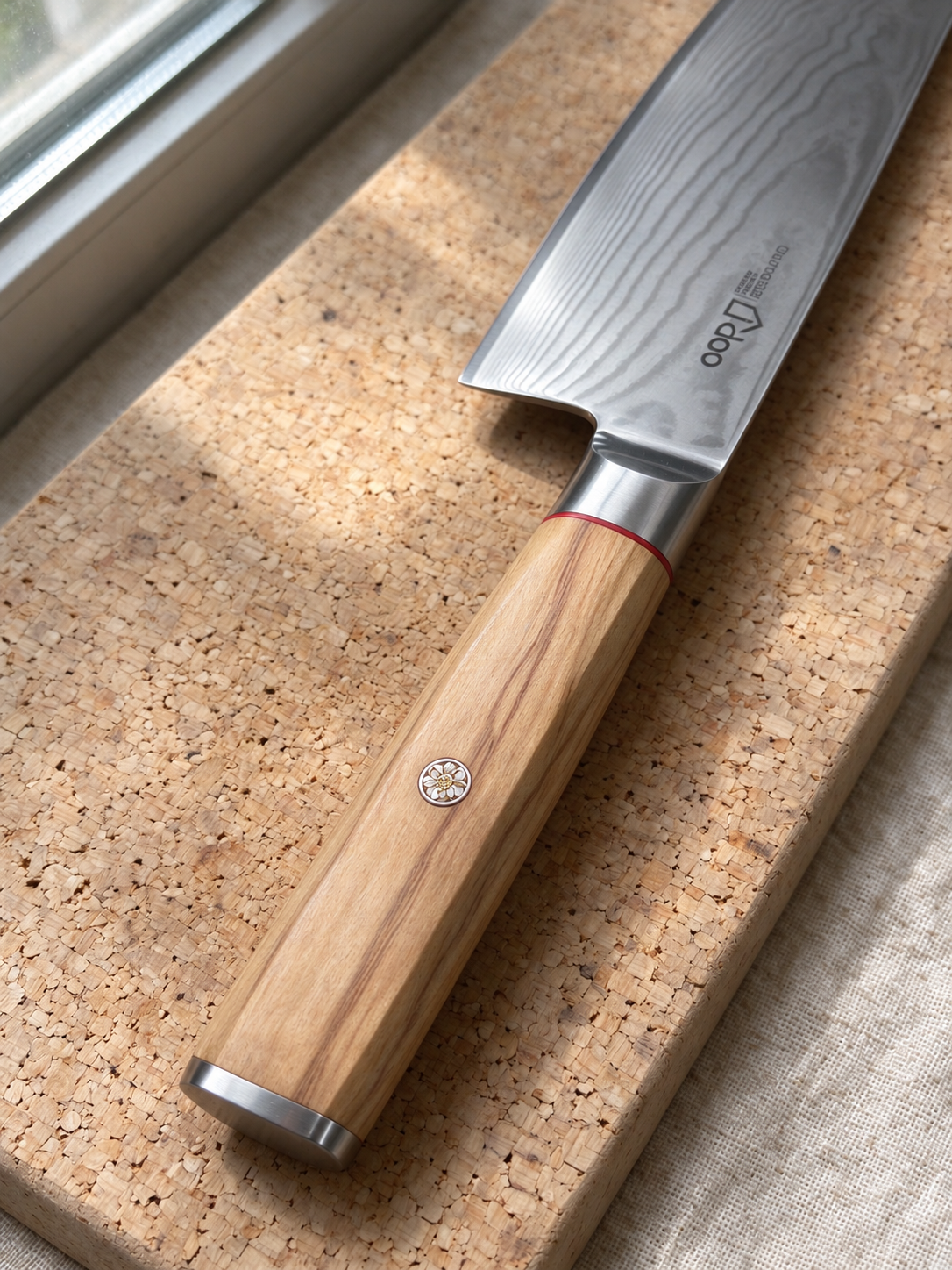 Bondi olive wood handle and Damascus blade detail by a sunlit window