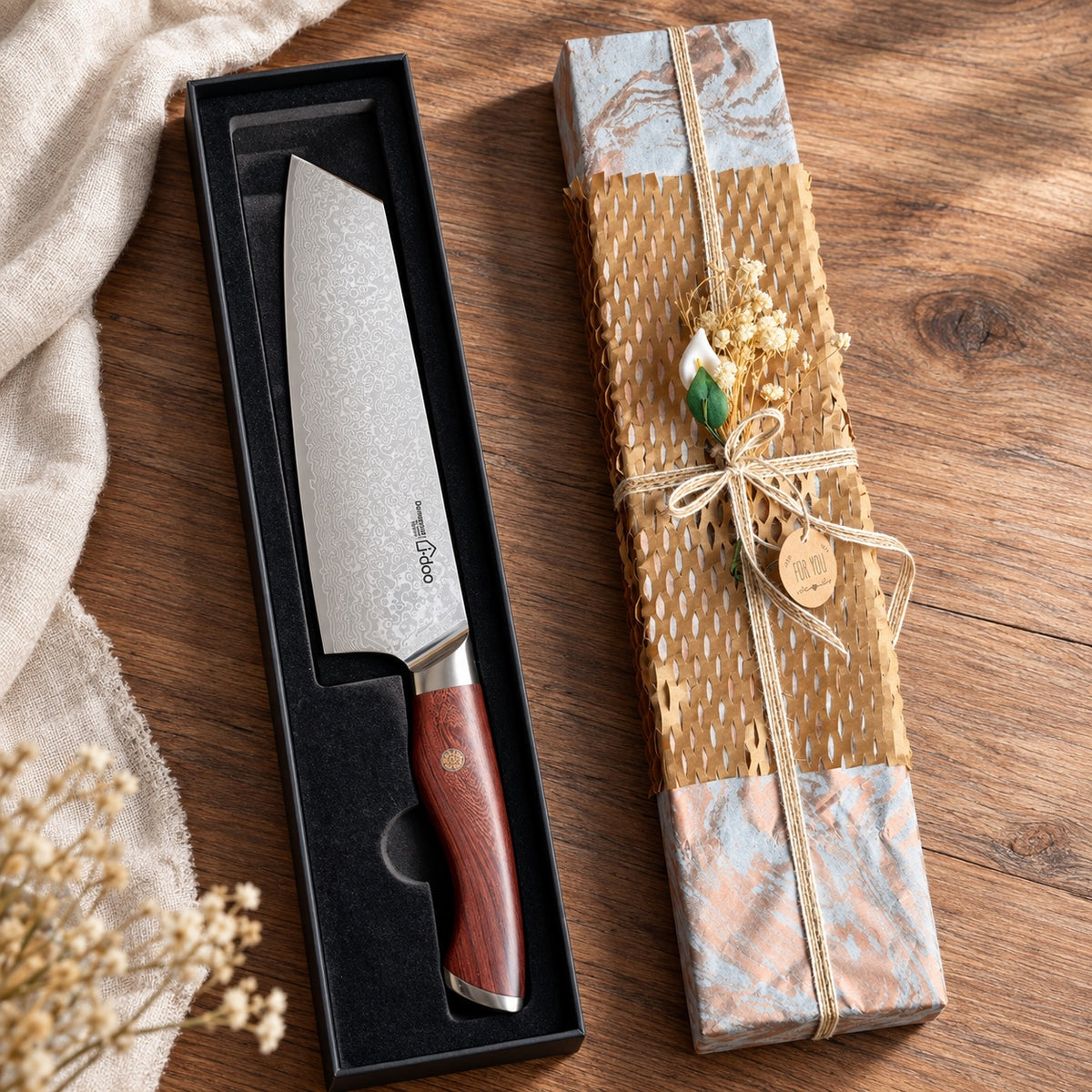 JD Damascus knife in its open black presentation box beside the wrapped gift box